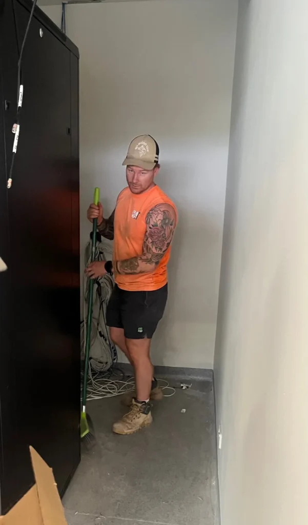 Electrician working beside an open switchboard at Bega Sports Complex
