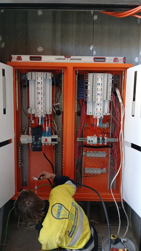 Electrician working on an open orange switchboard at Carroll College
